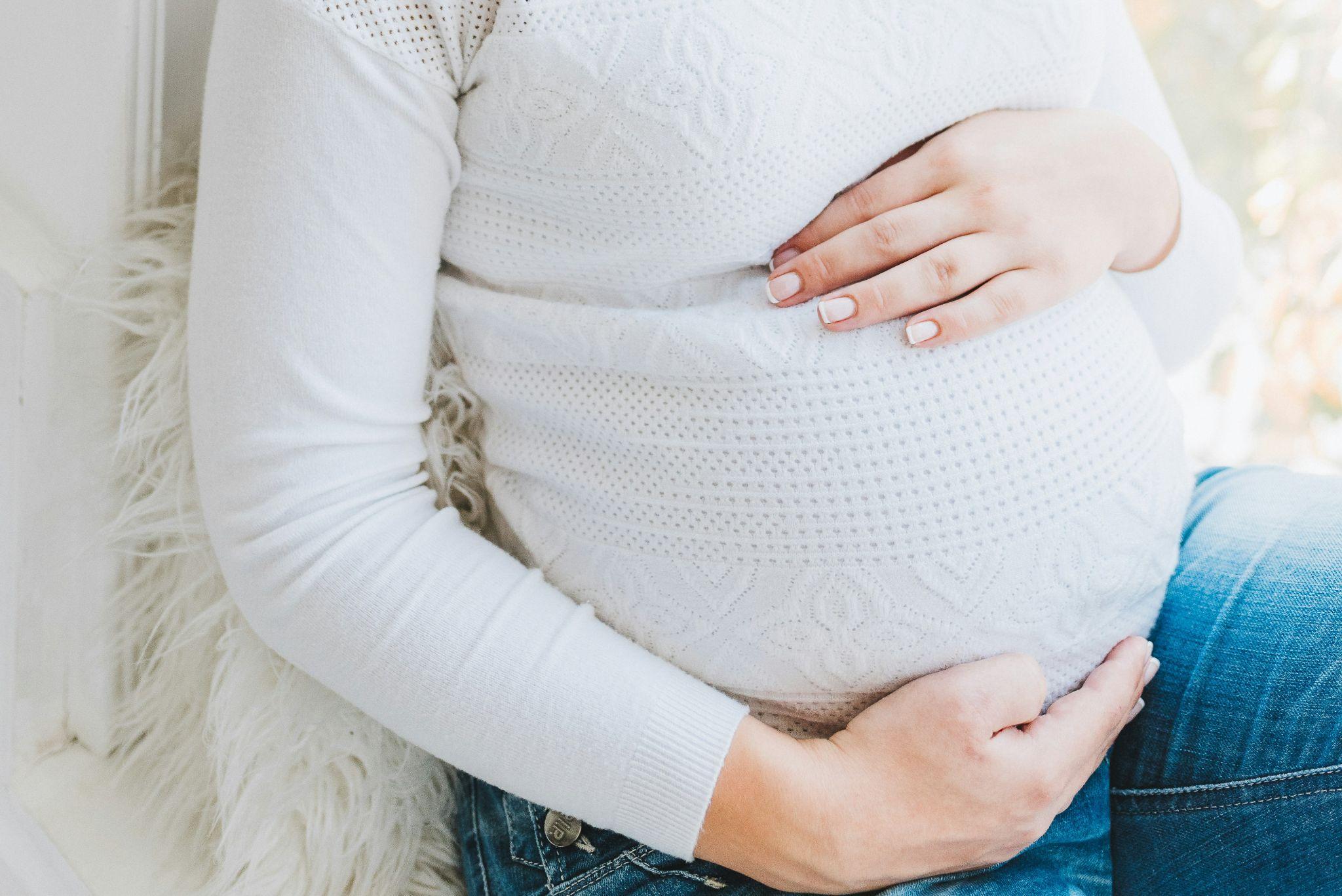 Closeup of a pregnant woman’s belly as she relaxes at home